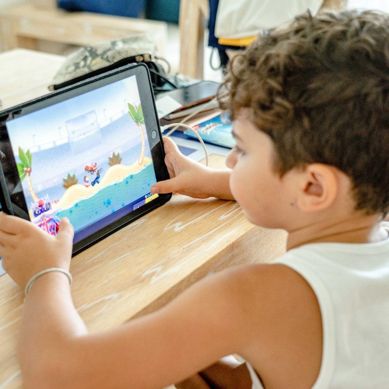 child using ipad at wooden table